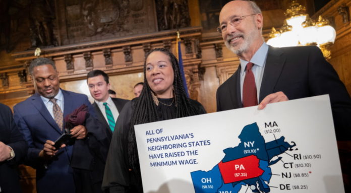 A Group of Judges hold a sign that reads 'ALL OF PENNSYLVANIA’S NEIGHBORING STATES HAVE RAISED THE MINIMUM WAGE'