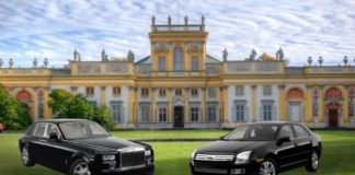 Two black used luxury vehicles are parked in front of a castle after leaving a used luxury car dealership.
