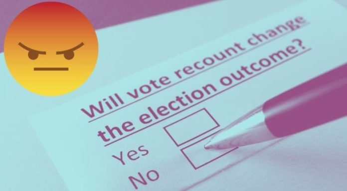 A grumpy emoji is shown above a ballot.