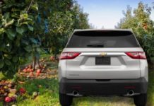 A silver 2022 Chevy Traverse is shown form the rear parked in an apple orchard.