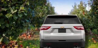 A silver 2022 Chevy Traverse is shown form the rear parked in an apple orchard.