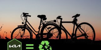 Bicycles are shown during a sunset near a Kia dealers logo and recycle symbol.
