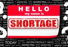 A sticker at a used car dealer says 'hello my name is shortage.'