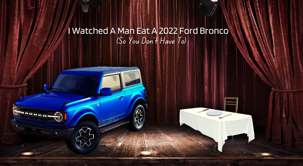 A blue 2022 Ford Bronco from a Ford dealer is shown on a stage.