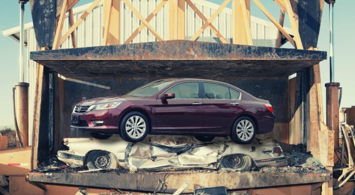 A maroon Honda Accord is shown in a crusher after leaving a lot that had used Hondas for sale.