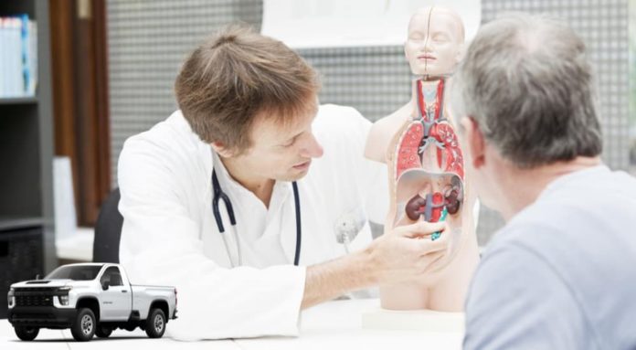 A doctor is shown with an anatomy model in front of a 2023 Chevy Silverado 3500 HD.