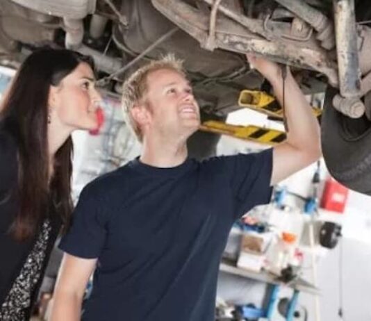 A woman and a man are shown looking at the bottom of a car at a Certified Pre-Owned Chevy truck dealer.