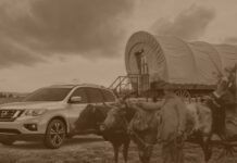 A Nissan Pathfinder for sale is shown next to a covered wagon.