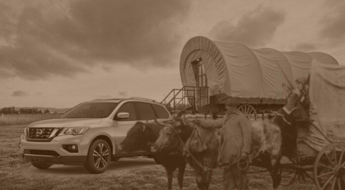 A Nissan Pathfinder for sale is shown next to a covered wagon.