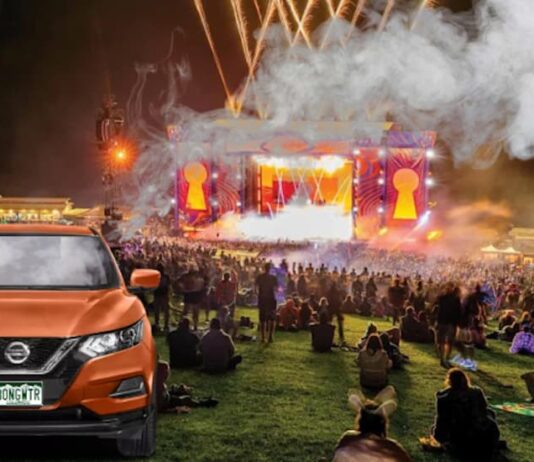 An orange Nissan Rogue for sale is shown at a festival.