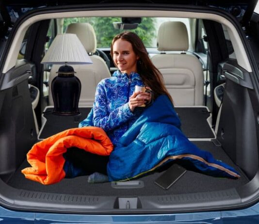 A person in a sleeping bag is shown in the trunk of a 2024 Buick Encore GX.