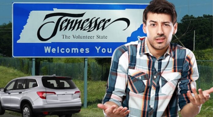 A man is shown standing in front of a billboard for Tennessee and a silver 2023 Honda Pilot for sale.