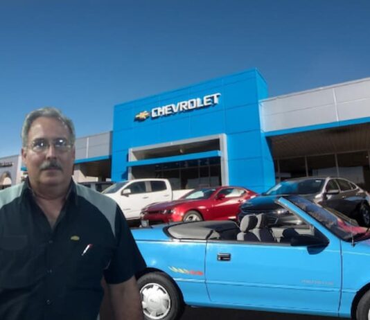 A person is shown standing in front a blue 1993 Geo Metro after trying to sell a 2024 Chevy Silverado 1500.
