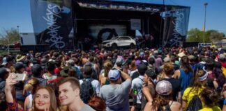 A white 2024 Chevy Equinox is shown on stage in front of a crowd and two people taking a photograph.