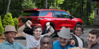 A group of people are standing near a red 2024 Chevy Traverse.
